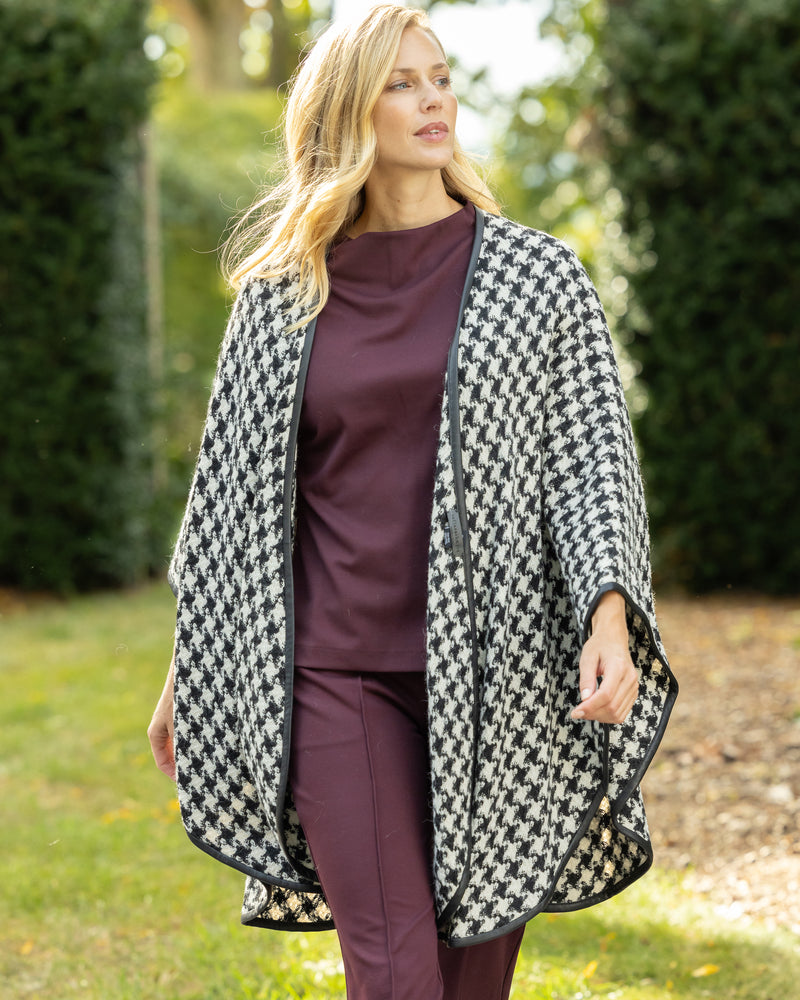 Woman Wearing Alpaca Wool Cape with Leather trim in Black and White Houndstooth Pattern.